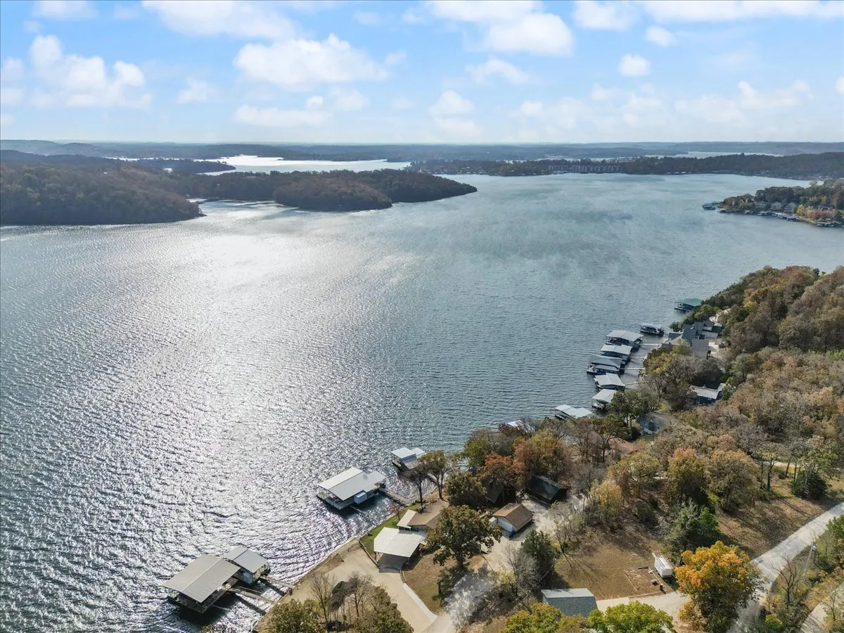 A broad, scenic view of the lake framed by boathouses, lush trees, and distant hills. The image reflects the larger environment guests are encouraged to explore, including opportunities for boating, hiking, and wildlife spotting along the lakeshore.