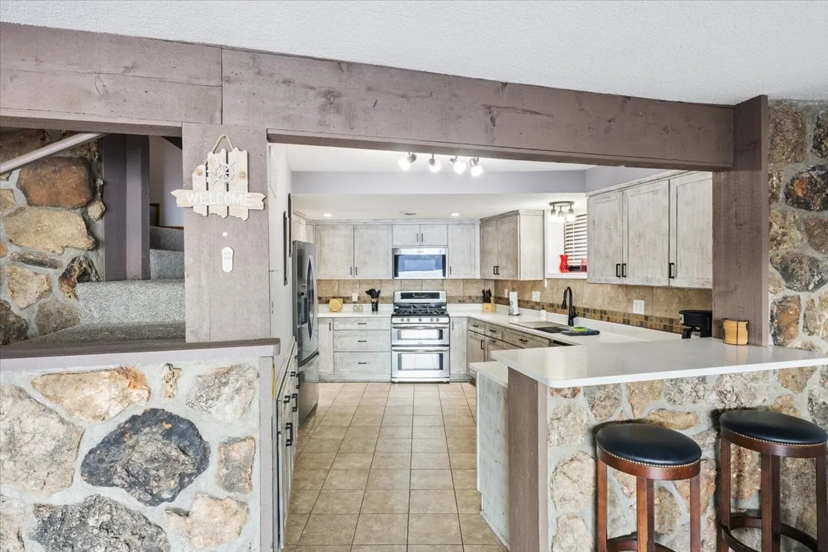 A remodeled kitchen with a prominent island, stone accent wall, and stainless steel appliances. The modern layout is designed for both meal prep and entertaining, aligning with the section's focus on effortless home-cooked meals and social interaction. The space is inviting and functional, ideal for group gatherings.